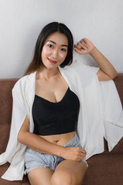 Evdeki kanepede oturan seksi Asyalı kadınlar.