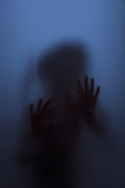 Mat camın arkasında bir çocuğun hayalet konsepti bulanık el ve vücut odaklanması
