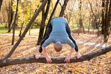 Sonbahar parkında yoga yapan sporcu adam. 