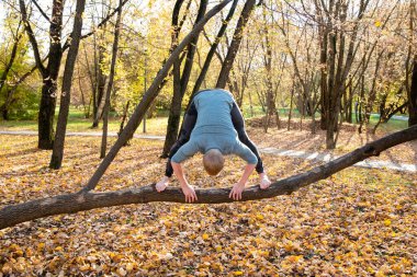 Sonbahar parkında yoga yapan sporcu adam. 