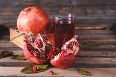  Olgun kırmızı açık nar, bir kutu dolusu nar, koyu ahşap zemin üzerinde bir bardak meyve suyu.