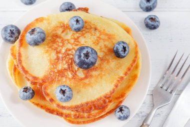 Yaban mersinli gözlemeler açık ahşap bir masada, bıçak, çatal, üst manzara