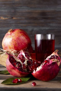  Olgun kırmızı açık nar, bir kutu dolusu nar, koyu bir tahta üzerinde bir bardak meyve suyu.