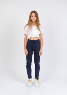 Mavi pantolonlu ve beyaz tişörtlü genç bir manken beyaz arka planda tam boy görünüyor.