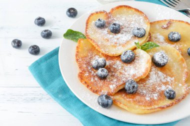 Böğürtlenli gözleme, bir tabakta nane ve pudra şekeri, beyaz arka plan manzaralı mavi peçete.