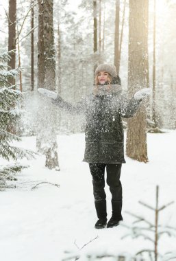 Bir genç beyaz kadın kışın ormana kar atıyor.,