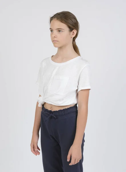 モデルサンプル ウエストハイポートレート ダークパンツの11歳の白い女の子 白い背景の白いシャツ — ストック写真