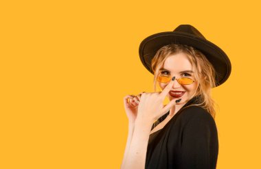 Siyah ceketli, güneş gözlüklü ve sarı şapkalı bir kadın. 