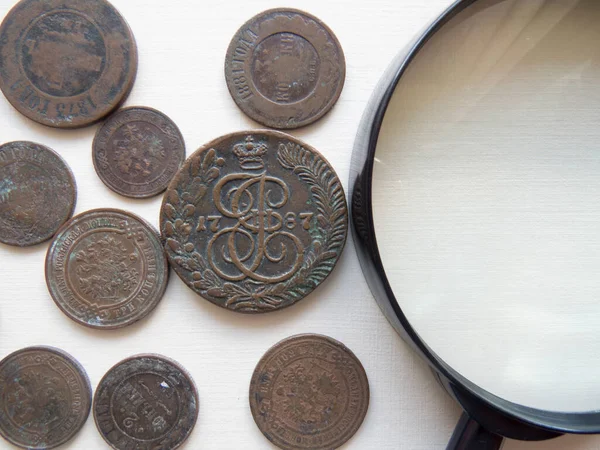 Pile of vintage metall (copper) coins. Magnifying glass and   coins of the Russian Empire in the background kopyur. Antikvariat. Numismatics vintage background