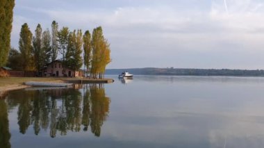 Nistru nehrinin kıyısında bir evi ve yüzen bir yatı olan manzara. Sonbahar mevsimi manzarası, renkli ağaçlar ve su yüzeyine yansıyan güzel gökyüzü.