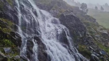 Romanya 'nın Karpat dağlarının Transfagarasan dönemeç rotasında Capra şelalesi. Sisli bir sonbahar sabahında kayalıklardan akan fırtınalı bir nehirle muhteşem bir manzara.