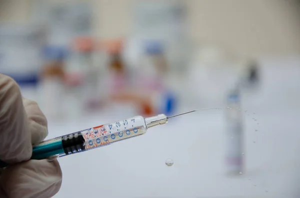 A syringe with a needle and splashes from it in the hand. syringe with medicine close-up.