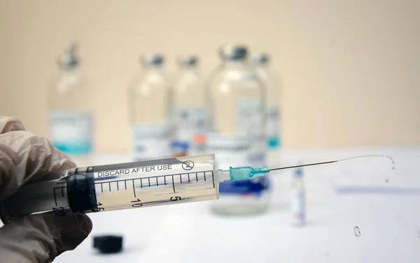 A syringe with a needle and splashes from it in the hand. syringe with medicine close-up.