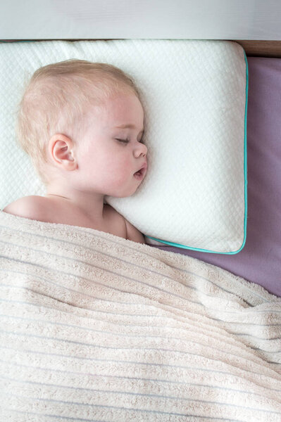 Portrait of a child sleeping in a bed on a pillow. Vertical photo