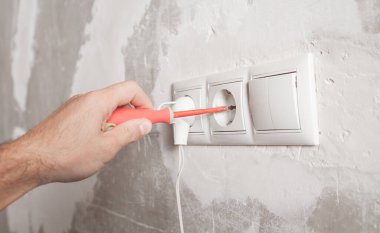 Elektrikçi evde elektrik prizini tamir ediyor..