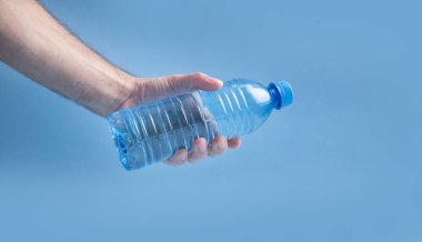 Erkek, plastik su şişesini tutuyor..
