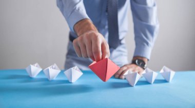 Beyaz tekneli kırmızı origami kağıt tekne tutan bir iş adamı. İş, Liderlik