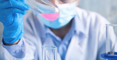 Laboratuvarda şişeyle çalışan bir kız..