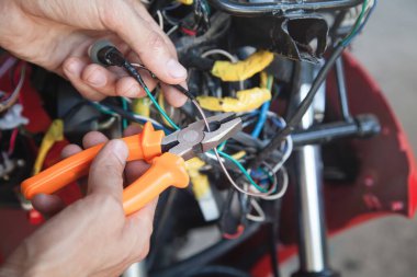 İşçi kerpetenle elektrik kablosu kesiyor.