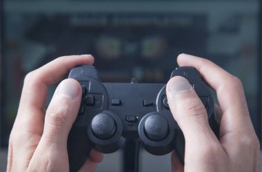 Eller joystick kullanıyor. Bilgisayar ekranında video oyunu oynanıyor