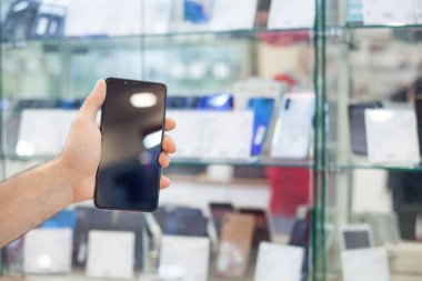 Elektronik mağazasında akıllı telefon gösteren bir adam.