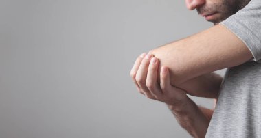 Dirsek ağrısı olan beyaz bir adam. Ağrı kesici kavramı