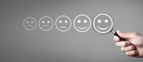 Büyüteçle erkek eli mükemmel bir gülümseme seçer. Müşteri hizmetleri. Beğeni. Geri bildirim