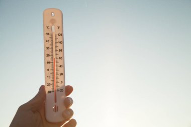 Gökyüzü arka planında el ele tutuşan termometre.
