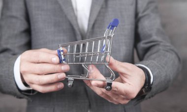 Elinde alışveriş arabası tutan bir iş adamı. Alışveriş.