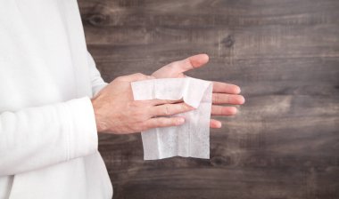 Adam ıslak mendille elini temizliyor..