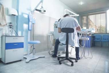Kürsüde oturan dişçi, diş kliniğinde çalışıyor..
