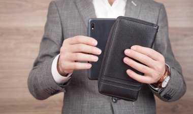 Akıllı telefon ve cüzdan gösteren bir adam.
