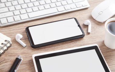 Kahve, akıllı telefon, kablosuz kulaklık ve ahşap masadaki diğer nesneler..