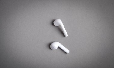 Gri arka planda beyaz kablosuz kulaklıklar..
