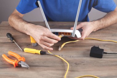 Beyaz adam kablosuz ağ yönlendiricisini tamir ediyor..