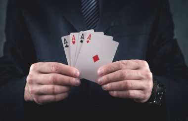 Takım elbiseli bir işadamı elinde iskambil kağıtlarıyla.
