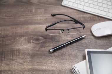 Ofis çalışma alanı. Bilgisayar klavyesi, gözlük, fare, tablet, not defteri, kalem..