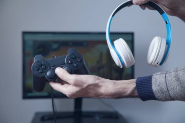 Kumarbaz elinde joystick ve kulaklık tutuyor..