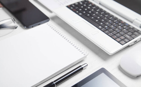 White laptop and business objects on the white desk.