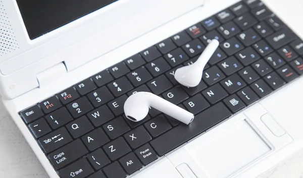 Laptop Klavyesinde Beyaz Kablosuz Kulaklıklar — Stok fotoğraf