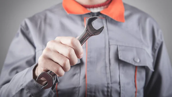 Man wearing a uniform holding a wrench.