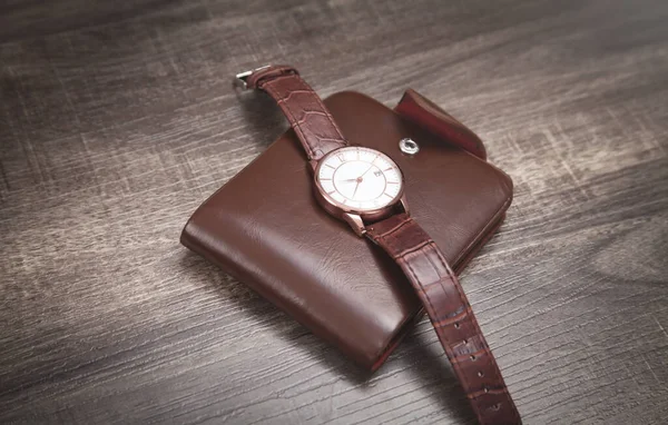 木製の背景に茶色の腕時計と財布 — ストック写真