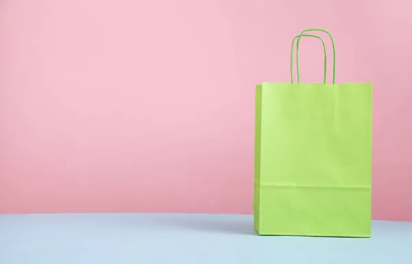 stock image Green shopping bag on pink and blue background.