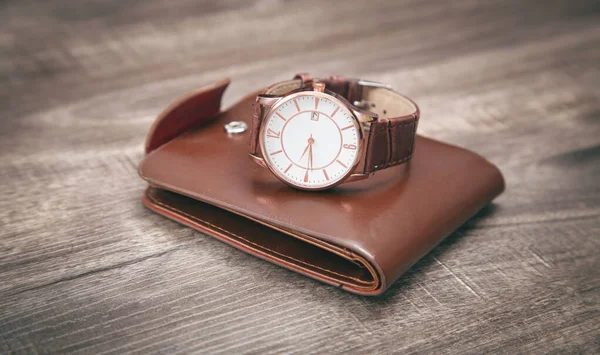 木製の背景に茶色の腕時計と財布 — ストック写真