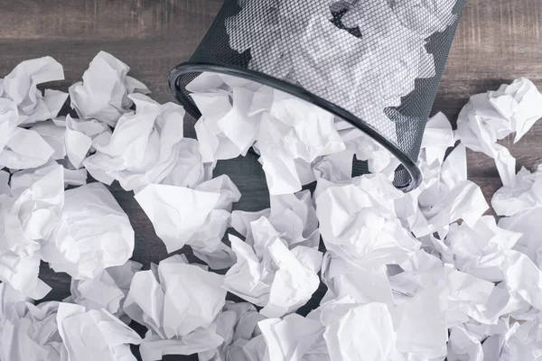 Crumpled papers in the trash can.