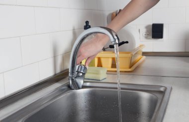 Kadın mutfakta musluk açıyor..