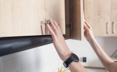 Beyaz kadın mutfak kapısının mobilyalarını açıyor..