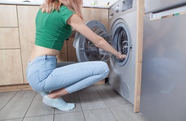 Beyaz kadın çamaşır makinesinin kapısını açıyor..