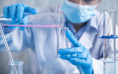 Laboratuvarda şişeyle çalışan bir kız..