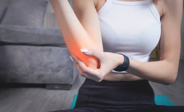 Dirsek ağrısı çeken genç bir kadın. Evde egzersiz yap.